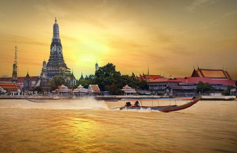 Sunset over Temple of Dawn Bangkok from Chao Phraya River with boat