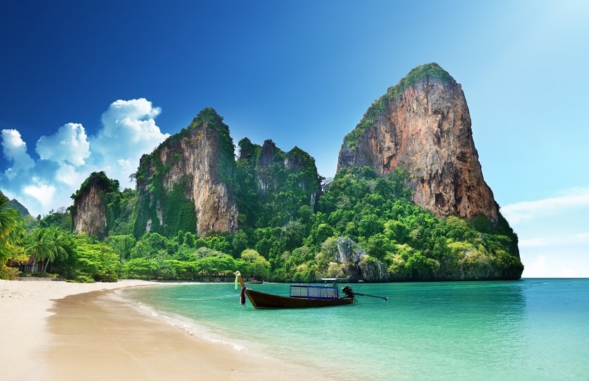 Traditional Thai longtail boat off Railay Beach with limestone cliffs